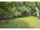 Lush backyard featuring a well-maintained lawn and a wooden deck, surrounded by mature trees and foliage at 1023 Chartley Sw Dr, Lilburn, GA 30047