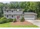 Charming two-story home with gray siding, red door, attached garage and a well-manicured front yard at 1023 Chartley Sw Dr, Lilburn, GA 30047