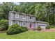 Two-story home featuring gray siding, a bright red door and lush greenery adding curb appeal to the front yard at 1023 Chartley Sw Dr, Lilburn, GA 30047