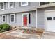 Close up of the home's entryway, featuring a bright red door, stone accents, and gray siding at 1023 Chartley Sw Dr, Lilburn, GA 30047
