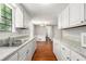 Galley kitchen with white cabinetry, hardwood floors and laminate counters open to the dining area at 1023 Chartley Sw Dr, Lilburn, GA 30047
