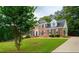 Traditional brick home with lush green lawn and mature trees creating a picturesque suburban setting at 1200 Larson Sw Ln, Marietta, GA 30064