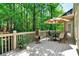 Back deck overlooking a wooded area with outdoor seating and an umbrella covered table at 1477 Edenham Ln, Cumming, GA 30041