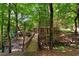 Backyard featuring a wooden walkway leading to a porch, all enveloped by lush trees and natural surroundings at 1477 Edenham Ln, Cumming, GA 30041