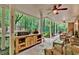 Covered patio with a grill station, wood cabinets, rattan seating, and a view of the wooded backyard at 1477 Edenham Ln, Cumming, GA 30041