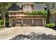 Front exterior view of a three-car garage with an attached pergola, potted plants, and manicured greenery at 1477 Edenham Ln, Cumming, GA 30041