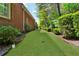 Grassy side yard featuring landscape edging, garden beds with hedges, and a brick house at 1477 Edenham Ln, Cumming, GA 30041
