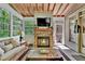 Relaxing sunroom features a stone fireplace, wood-paneled ceiling, and plenty of natural light from surrounding windows at 1477 Edenham Ln, Cumming, GA 30041