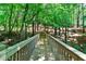Scenic view of a wooden walkway surrounded by lush trees and greenery, providing a tranquil passage at 1477 Edenham Ln, Cumming, GA 30041