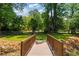 Backyard features a charming wooden bridge over a creek, surrounded by lush greenery and mature trees at 1377 Oak Grove Dr, Decatur, GA 30033