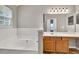 Bathroom featuring a soaking tub, large mirror, and extended vanity counter at 3514 Willgrove Way, Duluth, GA 30096