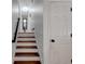 Well-lit staircase with white risers and wood treads, accented by a black handrail and a nearby closed white door at 944 Hardy Cir, Dallas, GA 30157