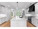 Modern kitchen featuring white cabinets, white backsplash, a large kitchen island, and black appliances and range hood at 206 Regester Way, Peachtree City, GA 30269
