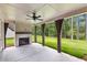 Covered outdoor patio with stone fireplace and ceiling fan overlooking manicured backyard at 206 Regester Way, Peachtree City, GA 30269