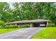 Brick home featuring a lush lawn, mature trees, and a convenient attached carport at 3549 Dogwood Dr, Powder Springs, GA 30127