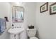 Charming powder room featuring a pedestal sink, framed mirror, and decorative artwork at 840 Yosemite Dr, Suwanee, GA 30024