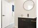 A modern bathroom with a black vanity, gold fixtures, and round mirror at 1810 Fairoaks Pl, Decatur, GA 30033