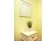 Charming vignette of a small, painted chest with decorative items and framed art with yellow walls at 118 Jasmine Way, Carrollton, GA 30180