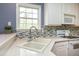 Bright kitchen featuring stainless steel appliances, stone countertops, a mosaic backsplash, and a double sink at 118 Jasmine Way, Carrollton, GA 30180