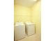 Yellow walled laundry room features washer and dryer and a shelf for storage at 118 Jasmine Way, Carrollton, GA 30180