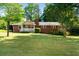 Charming single-story brick home with a cozy front porch, lush lawn, and mature trees at 1865 Briarlake Cir, Decatur, GA 30033