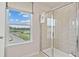 Bright bathroom featuring a glass-enclosed shower and a window providing natural light and neighborhood views at 210 Maycrest Path, Tucker, GA 30084