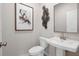 A modern powder room features a pedestal sink, decorative mirror, and contemporary artwork at 210 Maycrest Path, Tucker, GA 30084
