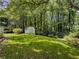 View of spacious backyard with lawn, landscaping, and outbuilding at 5841 Covered Wagon Trl, Lilburn, GA 30047