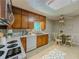 Kitchen with wooden cabinets, white appliances, and eat-in area at 5841 Covered Wagon Trl, Lilburn, GA 30047