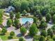 Aerial view of a community pool and clubhouse nestled among lush trees and well-maintained landscaping at 5875 Windjammer Pt, Cumming, GA 30041
