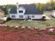 Spacious backyard with manicured lawn, mulched garden, and a white two-story home with a patio at 5875 Windjammer Pt, Cumming, GA 30041