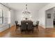 Elegant dining room with hardwood floors, wainscoting, a modern chandelier, and plantation shutters at 5875 Windjammer Pt, Cumming, GA 30041