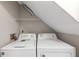 Functional laundry area featuring modern white washer and dryer units under a slanted ceiling at 8541 Westchester Dr, Douglasville, GA 30134