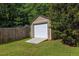 Tan shed in the backyard with a white garage door and concrete ramp next to a wood fence at 103 Sir Gregory Nw Mnr, Lawrenceville, GA 30044