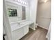 A bright bathroom featuring a large mirror, a well-lit vanity, and modern wood look flooring at 7007 Setters Way, Lithonia, GA 30038