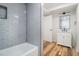 Bright bathroom features a tub with stylish blue tile, white vanity, and modern fixtures at 106 Hickory Ave, Fayetteville, GA 30215