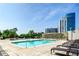 Outdoor pool with lounge chairs, a stone wall, and high-rise buildings in the background on a sunny day at 2233 Peachtree Ne Rd # 903, Atlanta, GA 30309