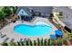Aerial view of community pool surrounded by chairs, with umbrellas, a community house, and landscaping at 240 Walker Avenue, Roswell, GA 30076