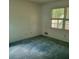 Simple bedroom with a window providing natural light and blue carpet at 9278 Seminole Rd, Jonesboro, GA 30236