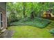 Large backyard featuring mature trees and a playhouse with a slide, surrounded by lush greenery at 220 N Springs Ct, Sandy Springs, GA 30328