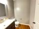 Powder room featuring hardwood floors, granite countertops, and decorative mirror at 790 Village Field Ct, Suwanee, GA 30024