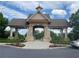 Community entrance featuring a stone pergola, landscaping, blue sky, and grey clouds at 790 Village Field Ct, Suwanee, GA 30024