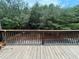 Weathered wood deck featuring dark wood railing with views of a wooded area and road at 790 Village Field Ct, Suwanee, GA 30024