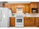 Bright kitchen features wood cabinets, white appliances, and a view to an adjacent dining space at 1294 Red Rock Rd, Acworth, GA 30101