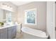 Bright bathroom with a soaking tub, gray vanity and a window providing natural light at 3794 Jack Vernon Cir, Powder Springs, GA 30127