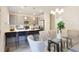 Open-concept dining area with modern light fixtures, a glass table, and a kitchen island with bar stools at 3794 Jack Vernon Cir, Powder Springs, GA 30127
