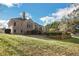 Backyard view featuring brick home, mature trees, tiered planting beds, and fencing at 6740 Mountain Lake Ln, Cumming, GA 30028