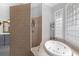 Bathroom showcasing a soaking tub and a tiled shower with glass block windows at 6740 Mountain Lake Ln, Cumming, GA 30028