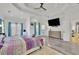 Open Primary bedroom with tray ceilings, a ceiling fan, hardwood floors, and a large screen tv at 6740 Mountain Lake Ln, Cumming, GA 30028