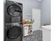 Well-organized laundry room with stacked washer and dryer and patterned tile flooring at 6740 Mountain Lake Ln, Cumming, GA 30028